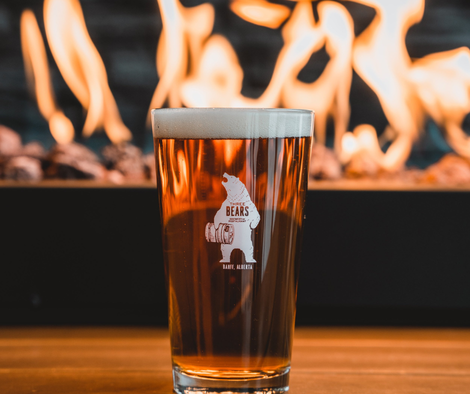 Three Bears Brewery Pint Glass with Beer in Front of Fire